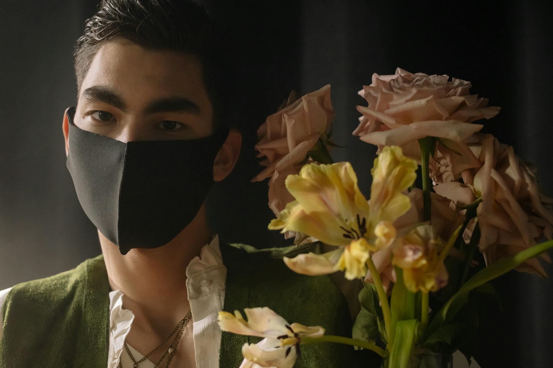 a man wearing black mask near the bouquet of flowers